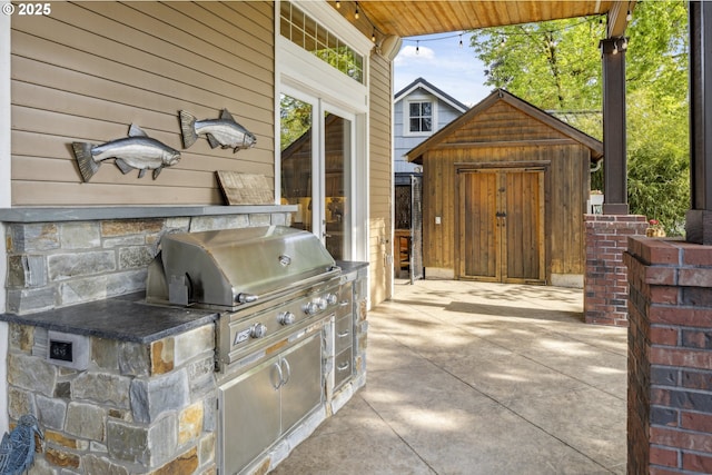 view of patio / terrace with a storage unit, an outdoor structure, exterior kitchen, and area for grilling