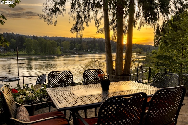 patio terrace at dusk featuring a water view and outdoor dining area