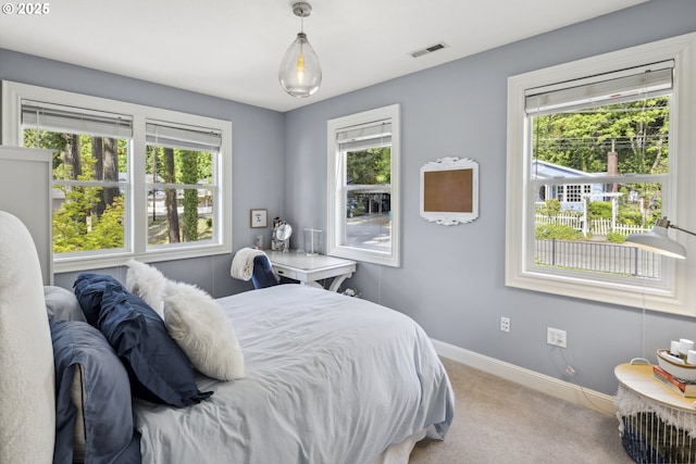 bedroom with carpet floors, baseboards, multiple windows, and visible vents