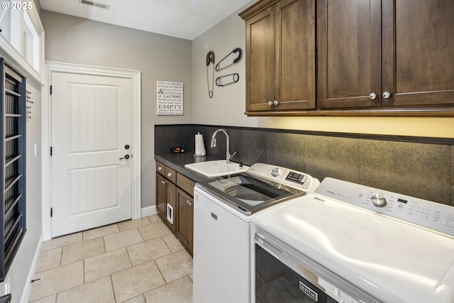 laundry room featuring visible vents, washing machine and clothes dryer, cabinet space, a sink, and light tile patterned floors