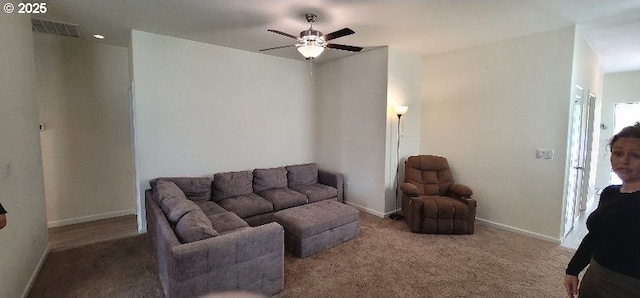 carpeted living area featuring ceiling fan and baseboards