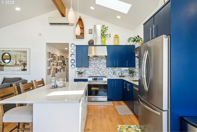 26280 Beach Dr, Rockaway Beach, OR 97136 - kitchen with stainless steel appliances, wall chimney range hood, a skylight, blue cabinetry, and light wood-style floors