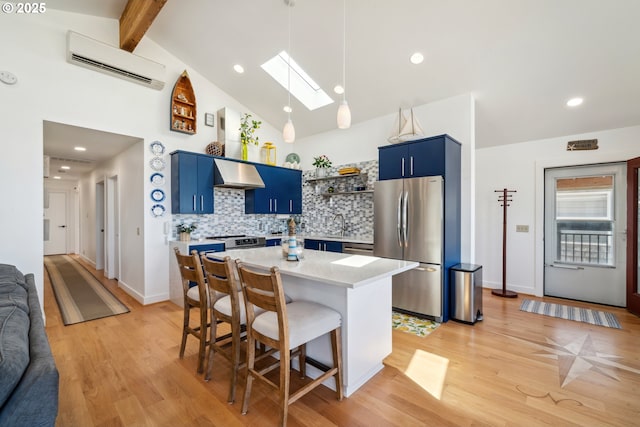 26280 Beach Dr, Rockaway Beach, OR 97136 - kitchen with appliances with stainless steel finishes, blue cabinetry, a wall unit AC, under cabinet range hood, and a skylight