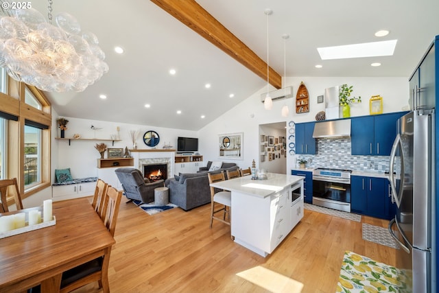26280 Beach Dr, Rockaway Beach, OR 97136 - kitchen featuring stainless steel appliances, blue cabinetry, beam ceiling, a lit fireplace, and light wood finished floors