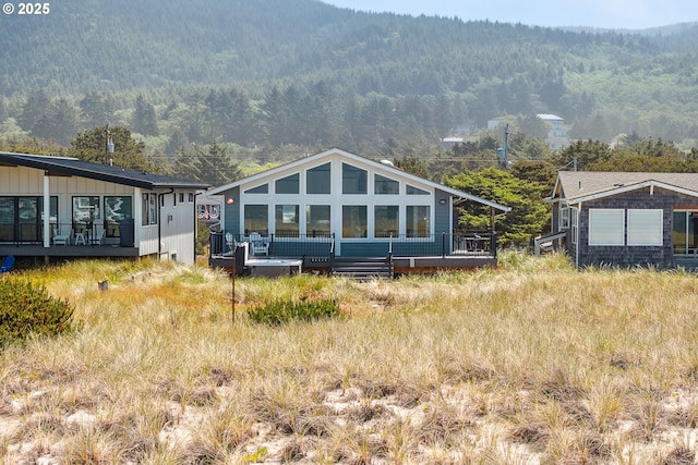 26280 Beach Dr, Rockaway Beach, OR 97136 - rear view of house featuring a deck with mountain view, a view of trees, and board and batten siding