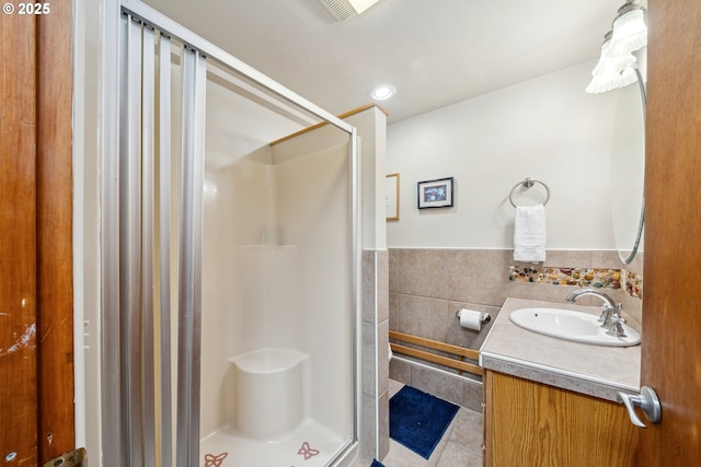 26280 Beach Dr, Rockaway Beach, OR 97136 - bathroom with a stall shower, vanity, tile patterned flooring, tile walls, and wainscoting