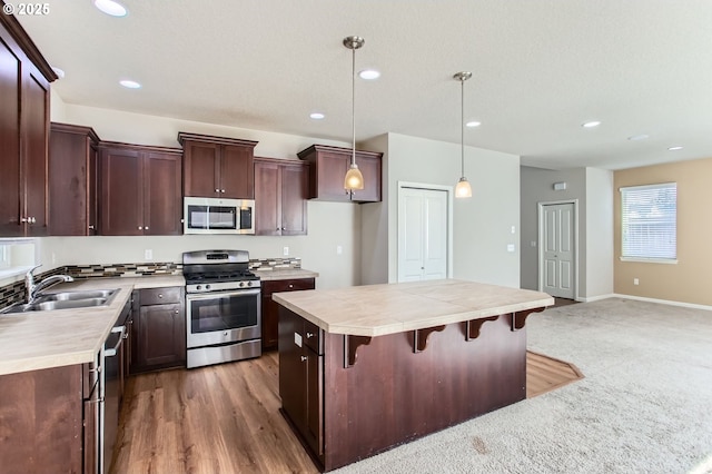 kitchen featuring a sink, light countertops, a center island, and stainless steel appliances