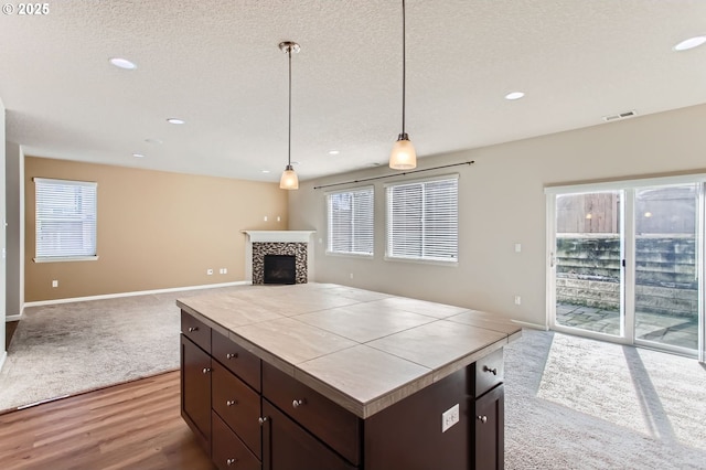 kitchen featuring visible vents, dark brown cabinets, open floor plan, tile countertops, and a fireplace