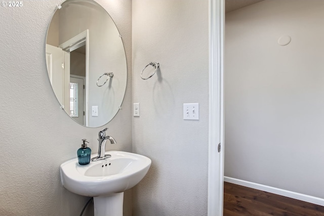 bathroom with a sink, baseboards, and wood finished floors