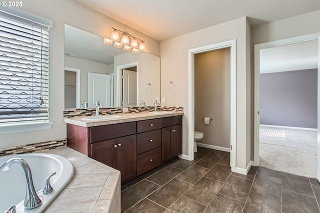 full bath with a garden tub, toilet, a sink, double vanity, and baseboards