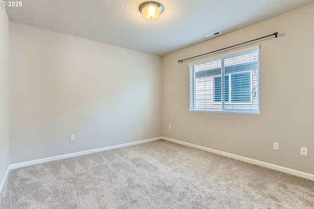 spare room featuring visible vents, baseboards, a textured ceiling, and carpet flooring