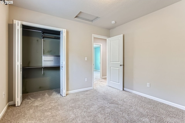 unfurnished bedroom with attic access, a closet, baseboards, and carpet floors