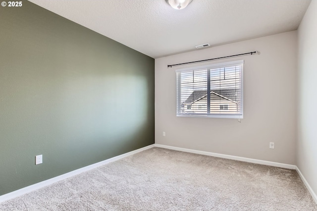 empty room with visible vents, a textured ceiling, baseboards, and carpet