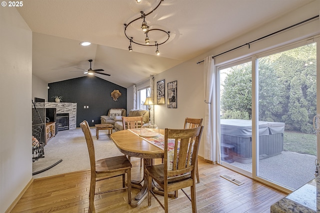 dining space with a fireplace, light hardwood / wood-style floors, lofted ceiling, and ceiling fan