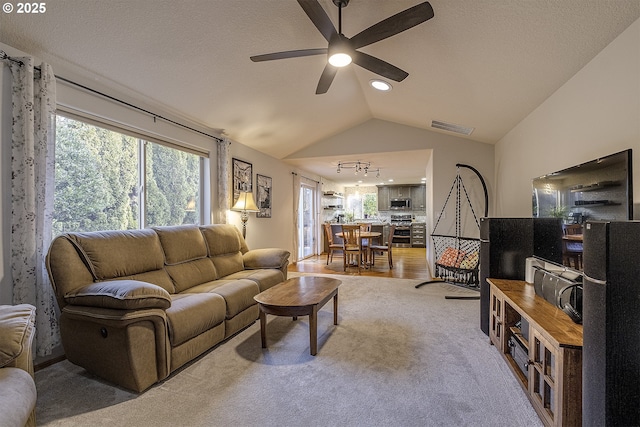 carpeted living room featuring ceiling fan, a textured ceiling, and vaulted ceiling