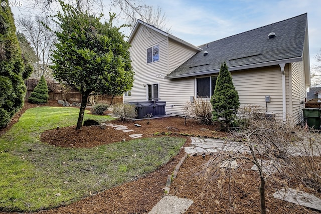 rear view of property featuring a lawn and a hot tub