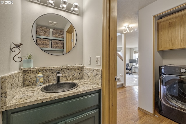 bathroom with vanity, hardwood / wood-style flooring, and washer / dryer