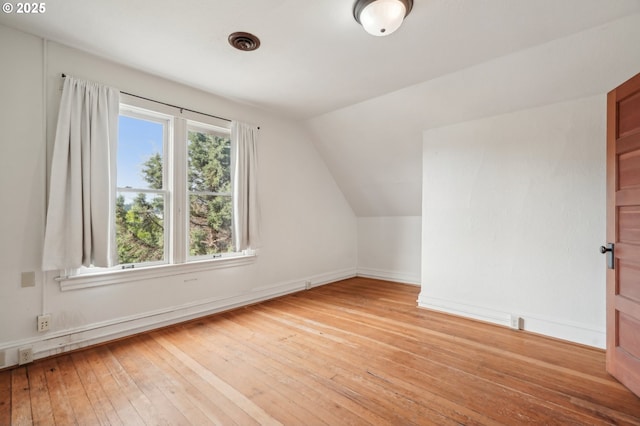 bonus room featuring light wood-type flooring, lofted ceiling, and baseboards