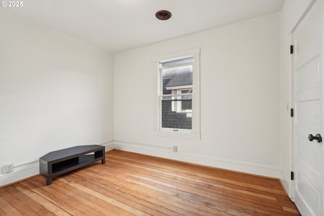 spare room with wood-type flooring and baseboards