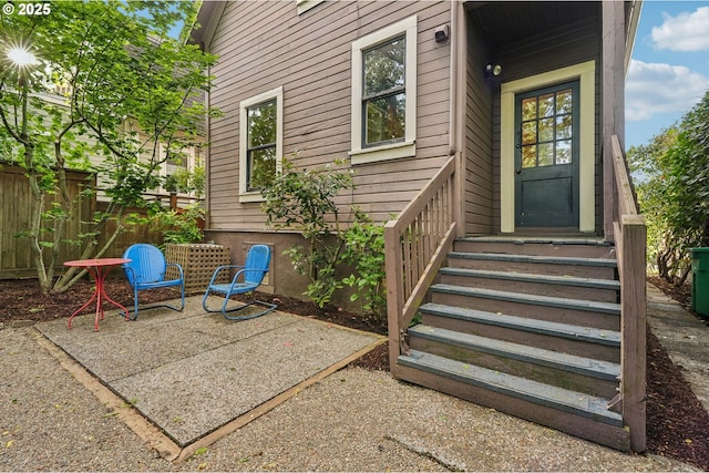 view of exterior entry featuring fence and a patio area