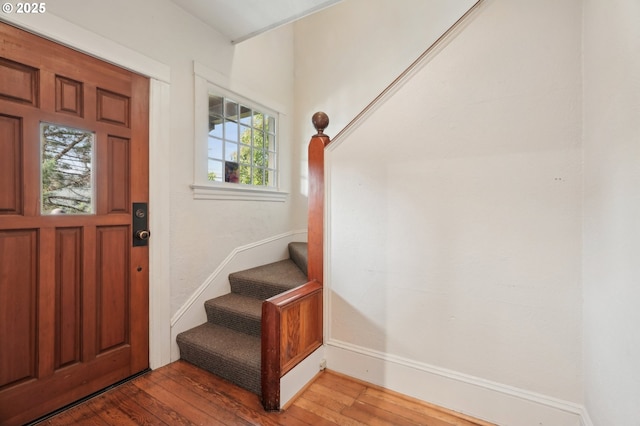 foyer entrance featuring stairway, hardwood / wood-style flooring, and baseboards