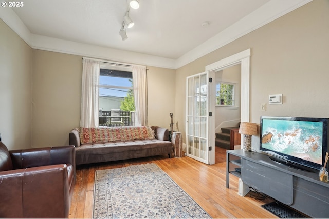 living area with light wood-style floors, rail lighting, and stairway