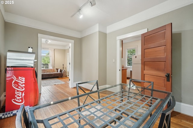 dining space with wood-type flooring, baseboards, and rail lighting