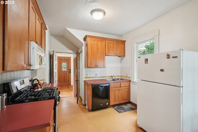 kitchen with white appliances, a sink, backsplash, and brown cabinets