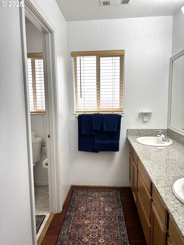 17239 Lumberview Rd, Brookings, OR 97415 - bathroom featuring toilet, wood finished floors, and double vanity