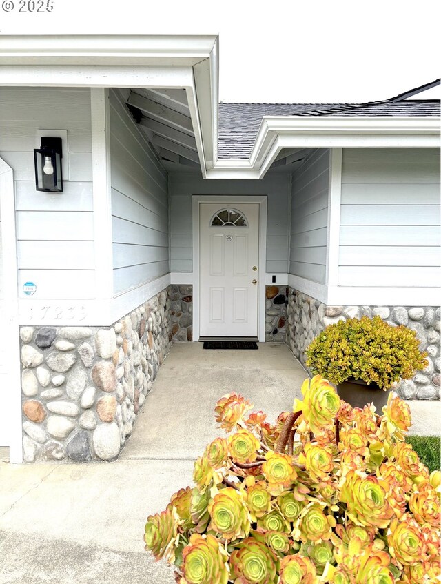 17239 Lumberview Rd, Brookings, OR 97415 - property entrance with stone siding, a shingled roof, and covered porch