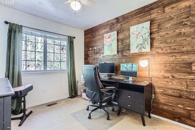 office with carpet, visible vents, ceiling fan, wooden walls, and baseboards