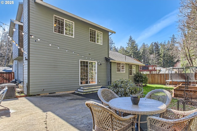 rear view of property featuring a trampoline, a patio, central AC unit, entry steps, and fence