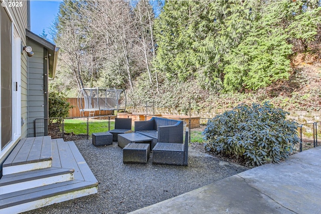 view of patio featuring a trampoline, fence, and an outdoor living space