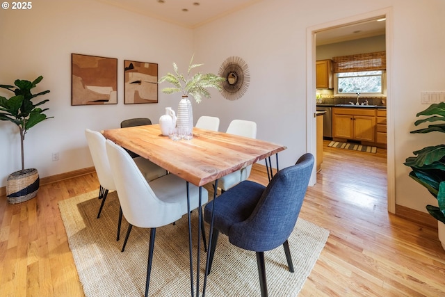 dining space featuring baseboards, light wood-type flooring, and ornamental molding