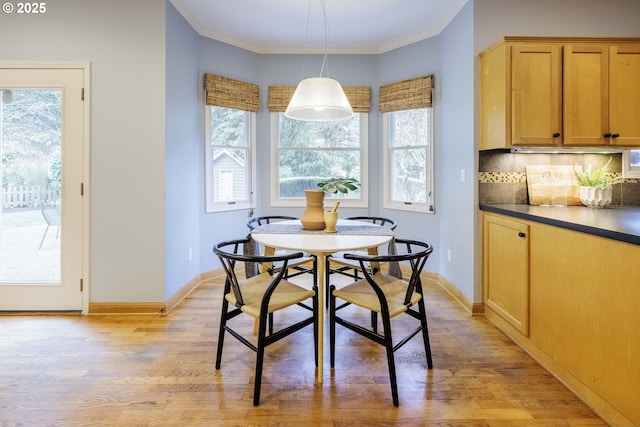 dining space featuring crown molding, light wood-style flooring, and baseboards