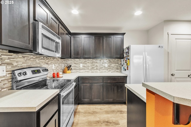 kitchen with light wood finished floors, tasteful backsplash, stainless steel appliances, light countertops, and recessed lighting