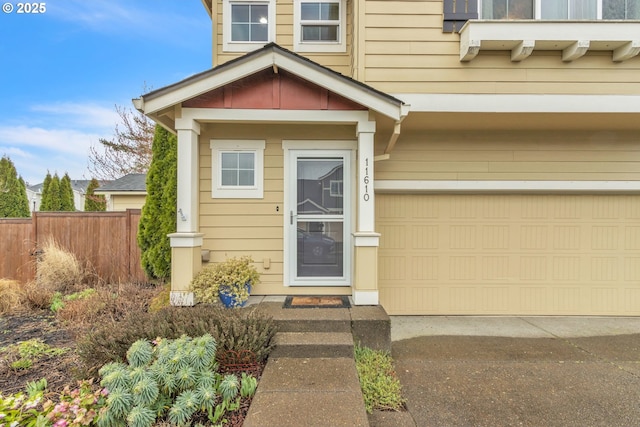 entrance to property with concrete driveway, fence, and an attached garage