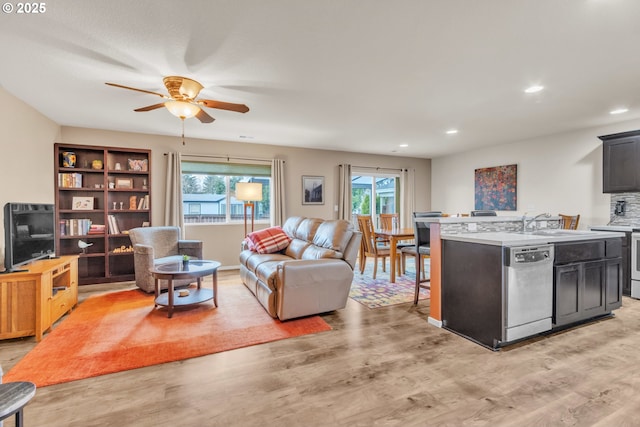 living room with light wood finished floors, a ceiling fan, and recessed lighting