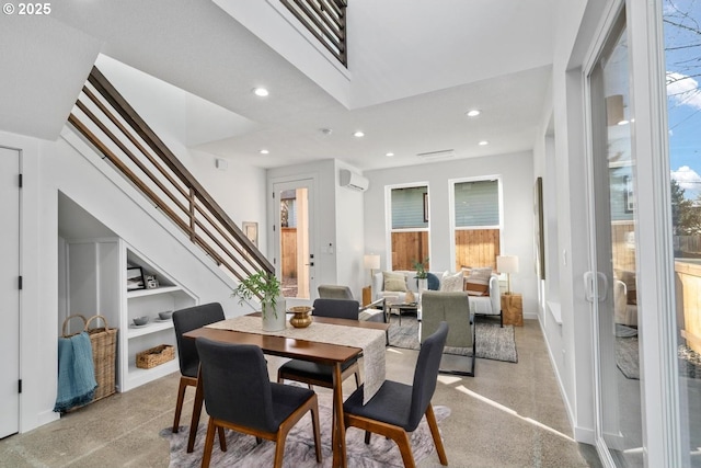 dining room with a wall unit AC, a healthy amount of sunlight, stairway, and built in features