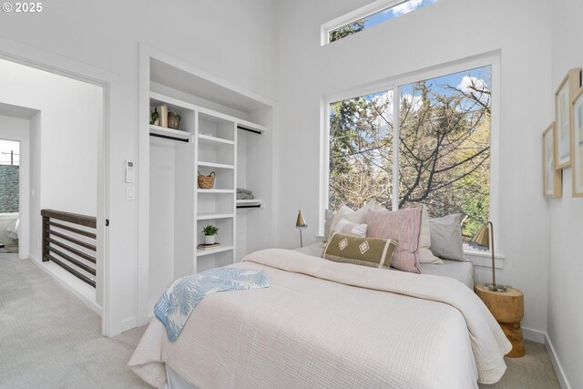 bedroom featuring multiple windows, baseboards, a closet, and light colored carpet