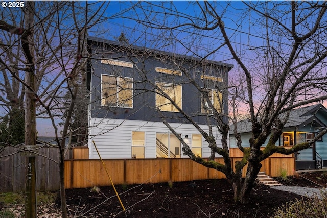 property exterior at dusk with a fenced front yard