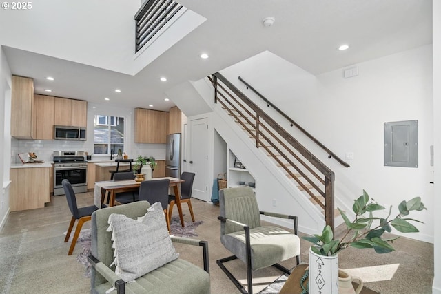 living area with a skylight, recessed lighting, stairway, electric panel, and baseboards