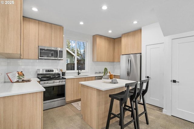 kitchen with modern cabinets, appliances with stainless steel finishes, a kitchen breakfast bar, a sink, and backsplash