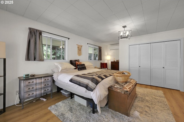 91760 Horse Creek Rd, Mckenzie Bridge, OR 97413 - bedroom featuring wood finished floors, a wall mounted air conditioner, a closet, and a chandelier