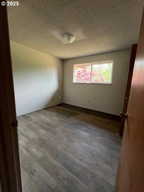 73927 Alder Grove Rd, Clatskanie, OR 97016 - unfurnished room featuring wood finished floors, a textured ceiling, and baseboards