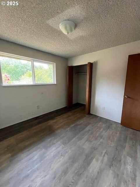 73927 Alder Grove Rd, Clatskanie, OR 97016 - unfurnished bedroom featuring a textured ceiling, dark wood-style floors, and a closet
