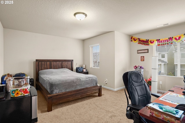 bedroom with visible vents, a textured ceiling, baseboards, and light carpet