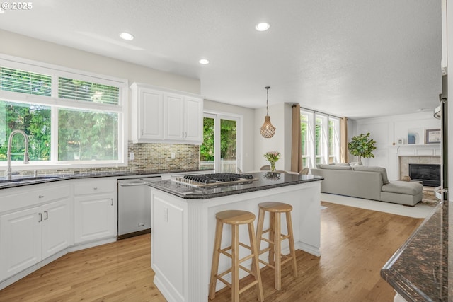 3852 Fairhaven Dr, West Linn, OR 97068 - kitchen with appliances with stainless steel finishes, a kitchen breakfast bar, tasteful backsplash, light wood-style flooring, and a kitchen island