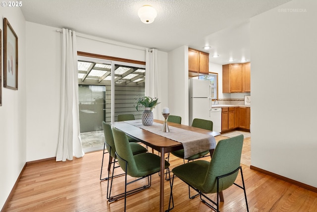 13140 SW Edgewood St, Portland, OR 97225 - dining space featuring light wood-style flooring, plenty of natural light, baseboards, and a textured ceiling