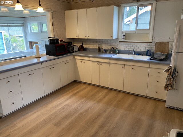 313 Taylor St, Ryderwood, WA 98581 - kitchen with decorative backsplash, light wood-style flooring, hanging light fixtures, white cabinetry, and a sink